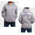 Hellgrauer Kapuzenpullover mit Kängurutasche, vorne links auf der Brust ein violettes Logo mit dem Schriftzug 'Volt' umgeben von zwölf Sternen in Kreisform. Auf der Rückseite in violetter Schrift der Text 'ZUKUNFT MADE IN EUROPE' mit einem Kreis aus zwölf Sternen rechts daneben. Die Person trägt dunkle Jeans, die Kapuze liegt locker auf dem Rücken.