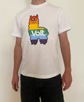 Weißes T-Shirt mit einem bunten Lama-Motiv in Regenbogenfarben. Auf dem Lama steht in weißen Buchstaben das Wort 'Volt'. Die Person trägt dunkle Hosen, der Hintergrund ist neutral.